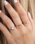 A delicate 14k yellow gold engagement ring, set with a center brilliant cut white diamond and smaller diamonds around it, in the shape of a geometric flower. 