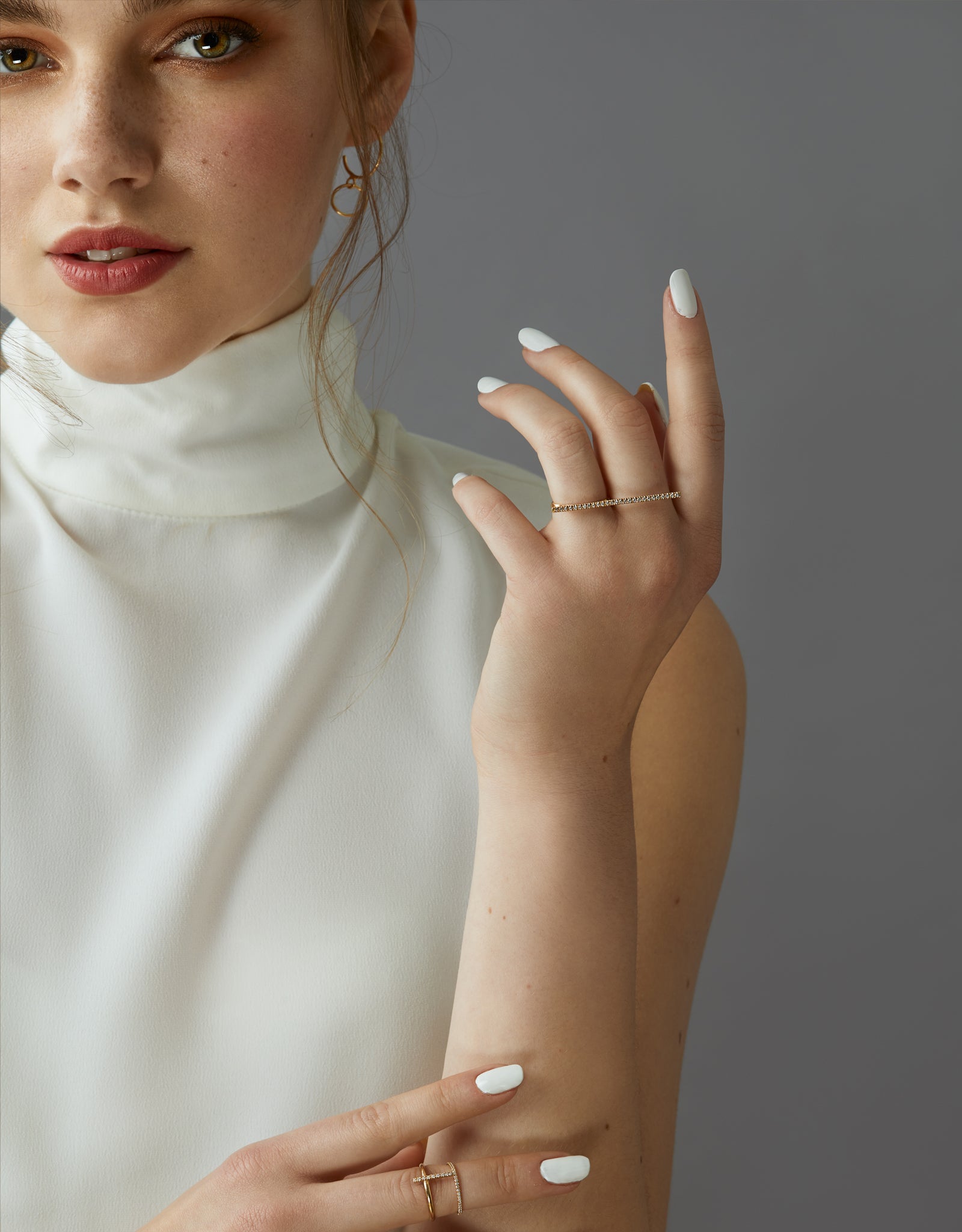 A dainty 14k yellow gold two finger ring, with a long bar set with white diamonds, that covers both fingers.