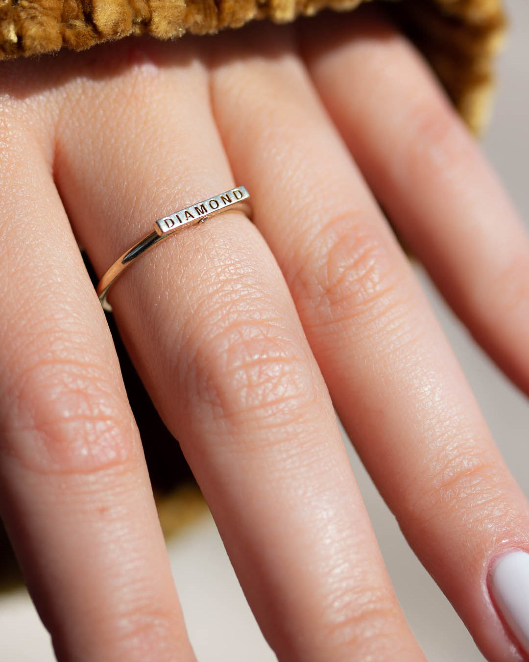 A delicate 14k yellow gold ring, engraved with DIAMOND on top and set with two tiny white diamonds.