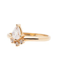 A 14k yellow gold engagement ring, set with a center pear cut white diamond and and halo of three small white diamonds. 