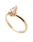 A 14k yellow gold engagement ring, set with a center pear cut white diamond and and halo of three small white diamonds. 