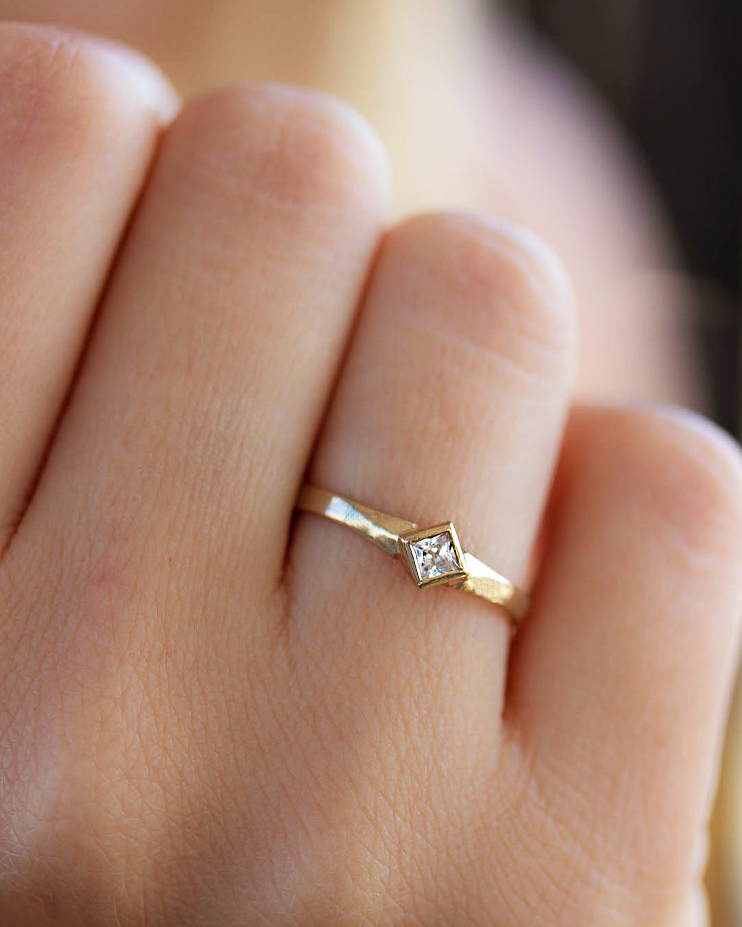 A delicate 14k yellow gold engagement ring set with a center 0.25 carat princess cut white diamond. 