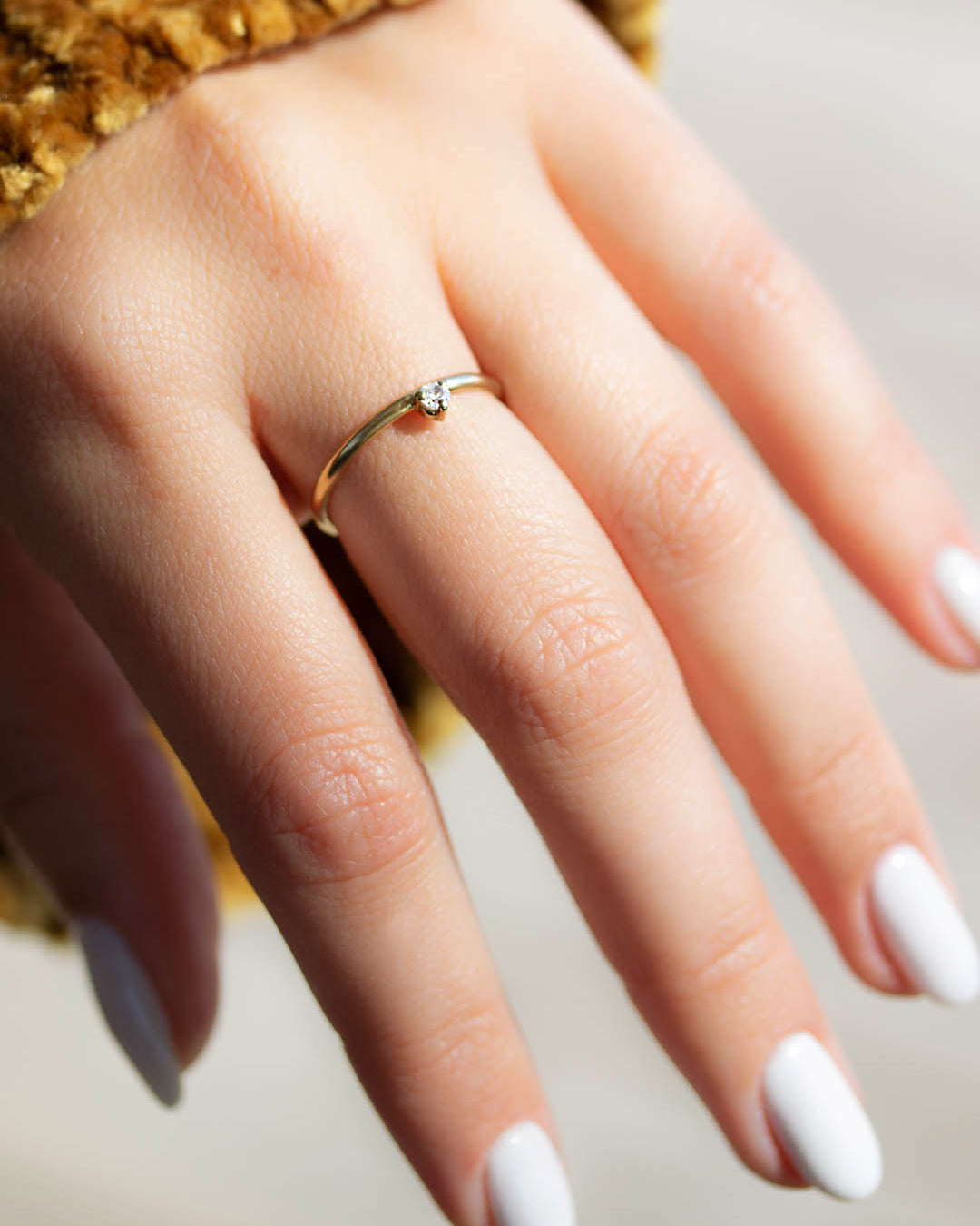 A dainty 14k yellow gold ring, set with one tiny, brilliant cut white diamond.