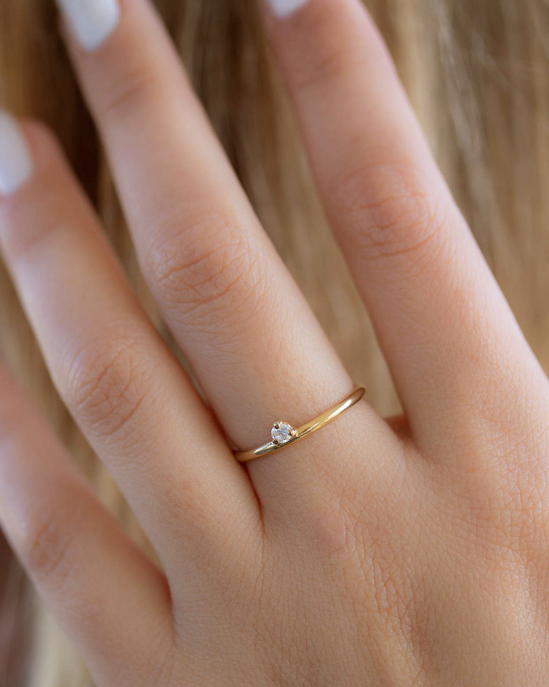 A dainty 14k yellow gold ring, set with one tiny, brilliant cut white diamond.